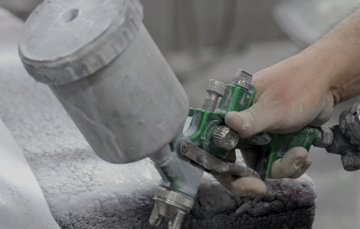 Aplikace automobilového laku stříkací pistolí v průmyslovém prostředí, ilustrující technická řešení testovaná přímo na výrobní lince.